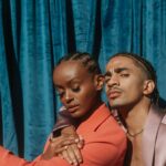 Two people posing against blue curtain.