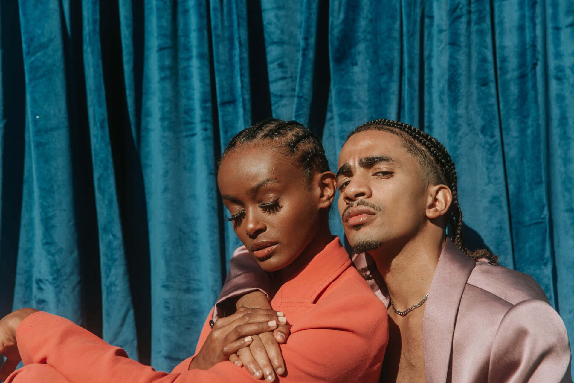 Two people posing against blue curtain.
