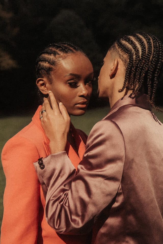 Two people embracing outdoors in stylish attire.