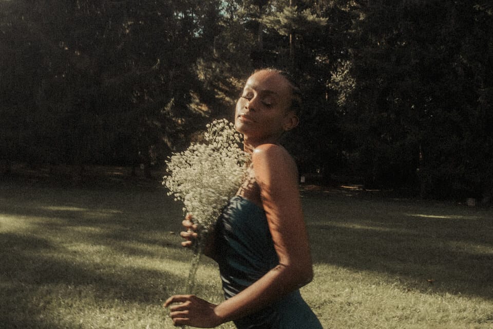 Woman holding flowers in sunny forest.