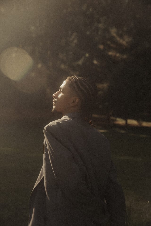 Person in suit looking at sunlight outdoors.