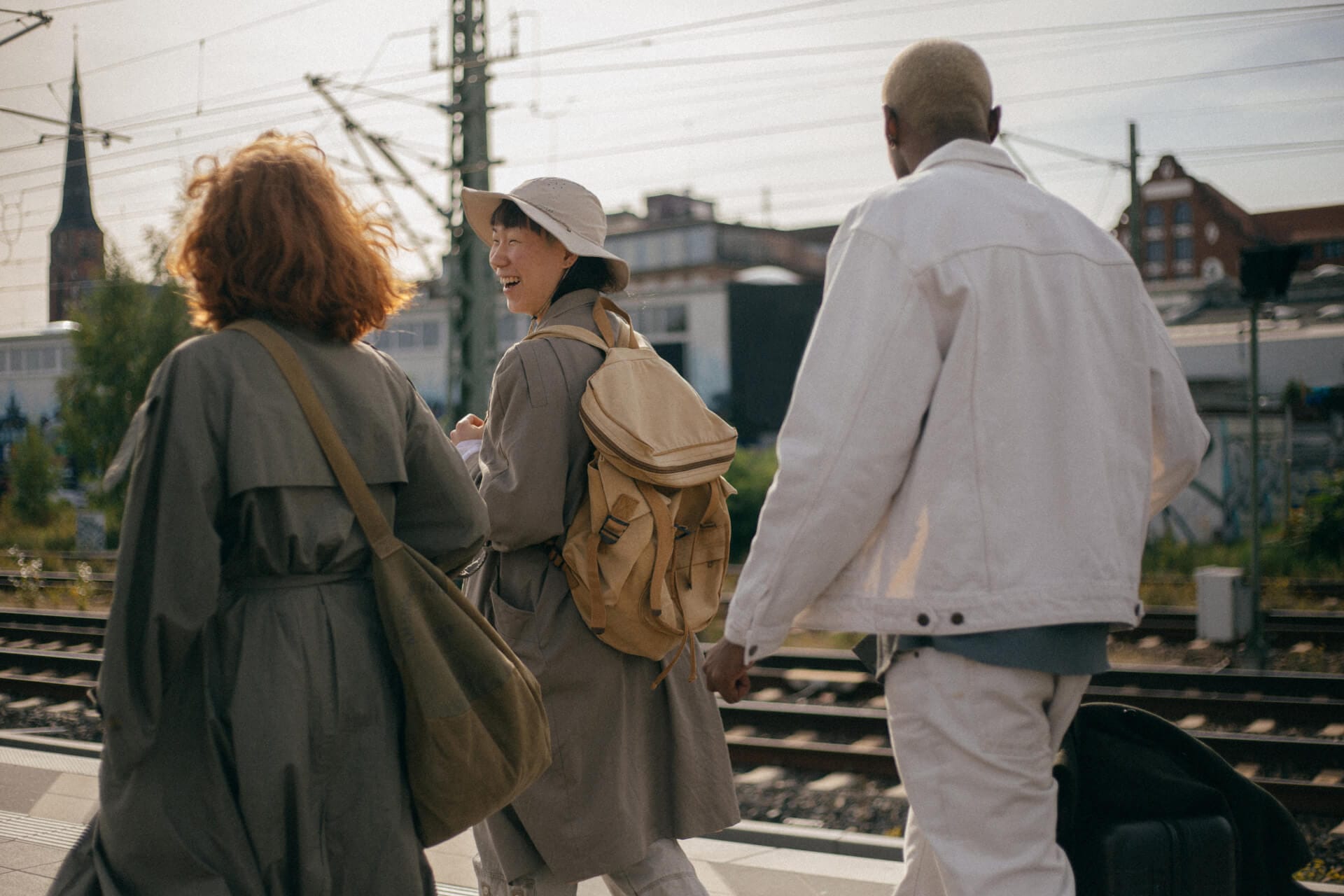 Three people walking at train station.