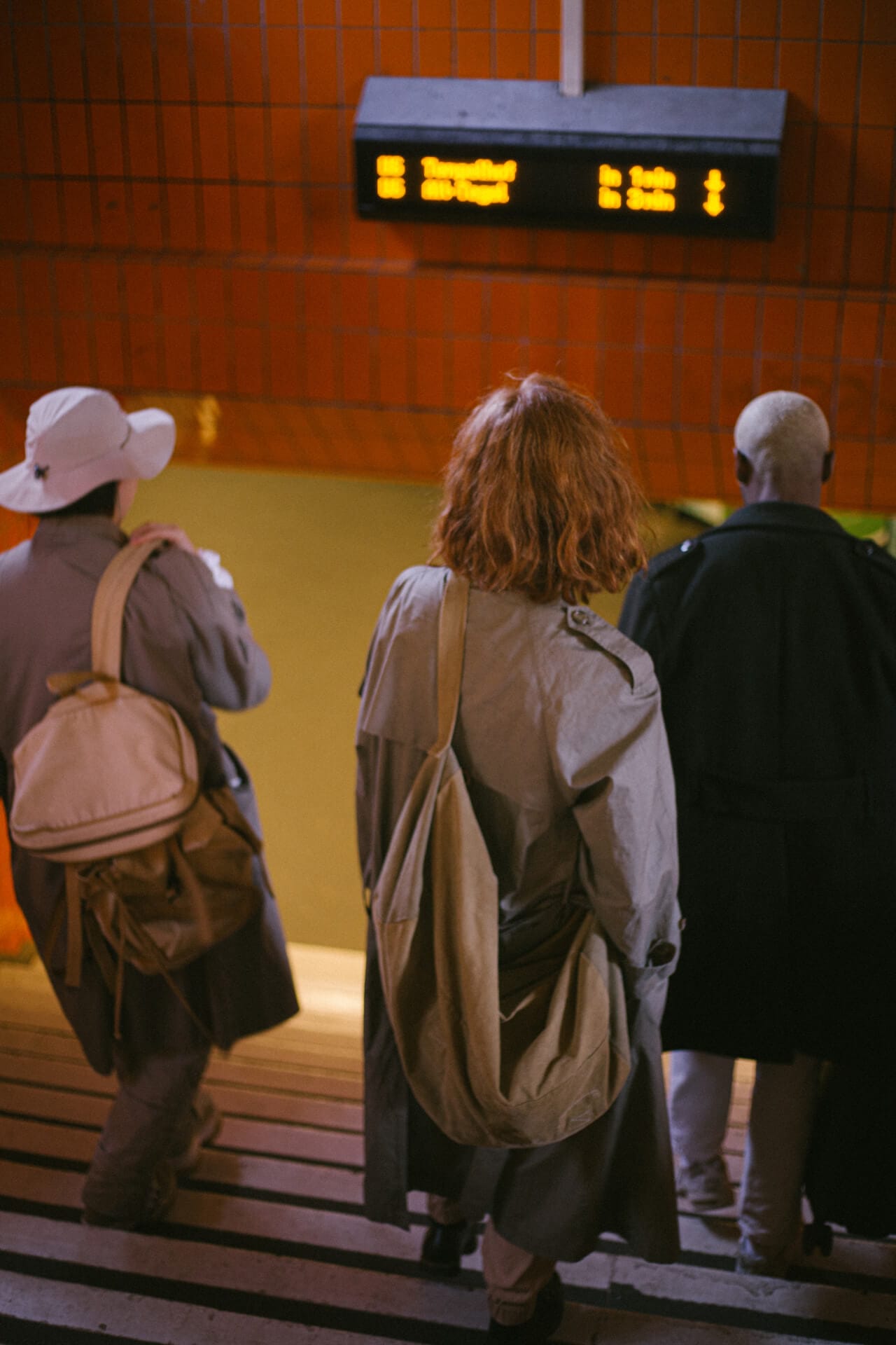 Three people descending subway stairs together.