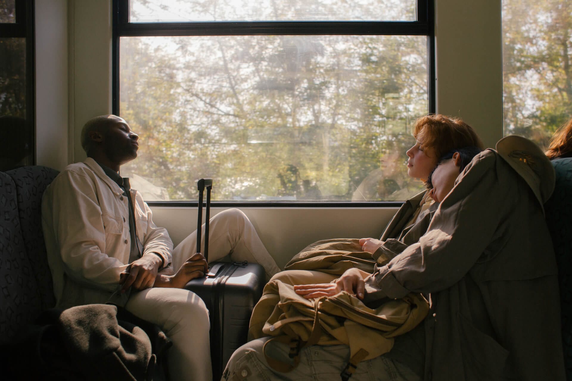Passengers sitting inside a train, sunlight streaming.