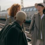 Three people chatting at train station.