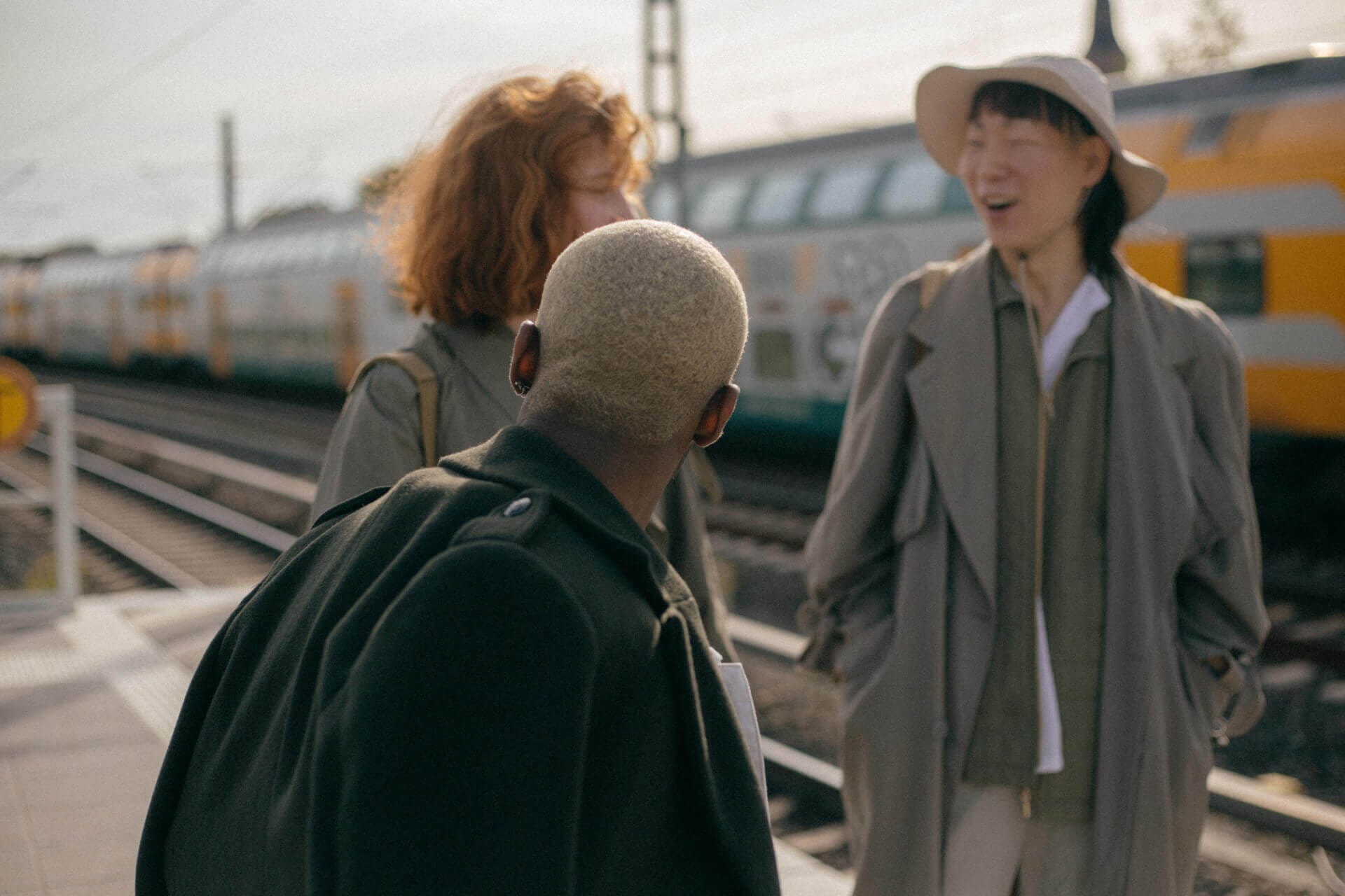 Three people chatting at train station.