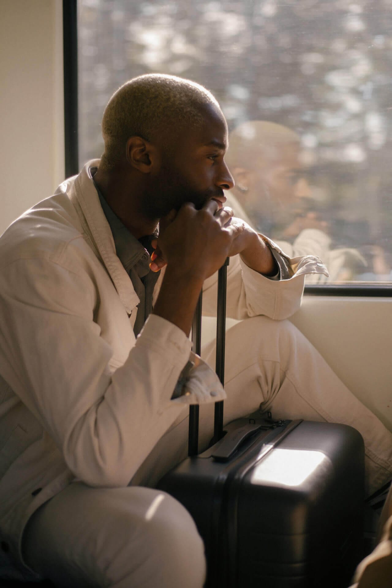 Man sitting with suitcase on train.