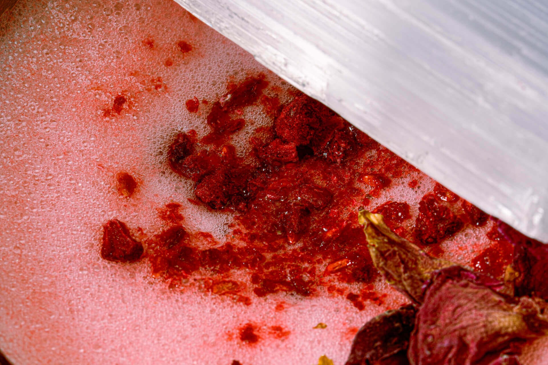 Red spices being ground with pestle.