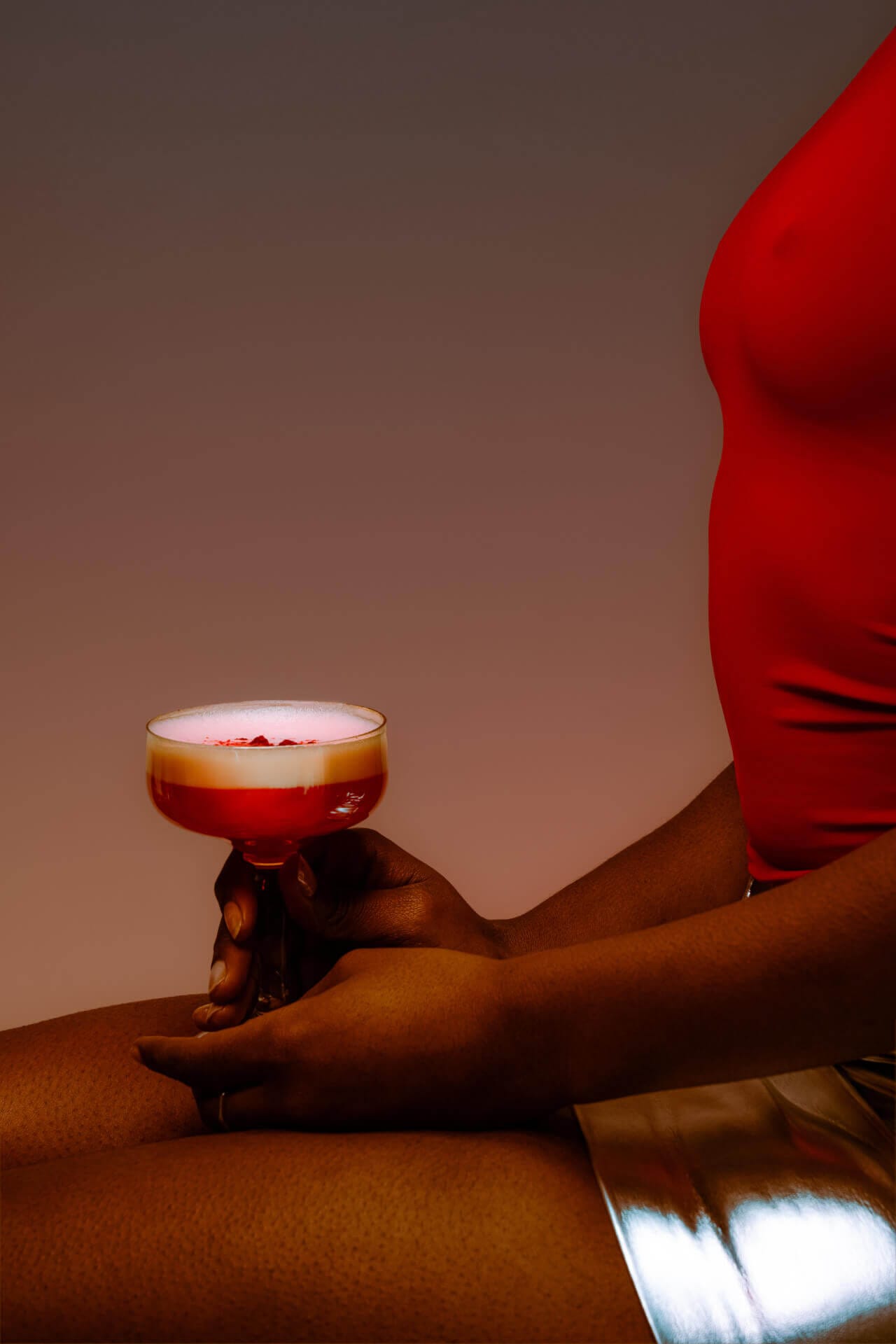 Person holding a cocktail in dim lighting.