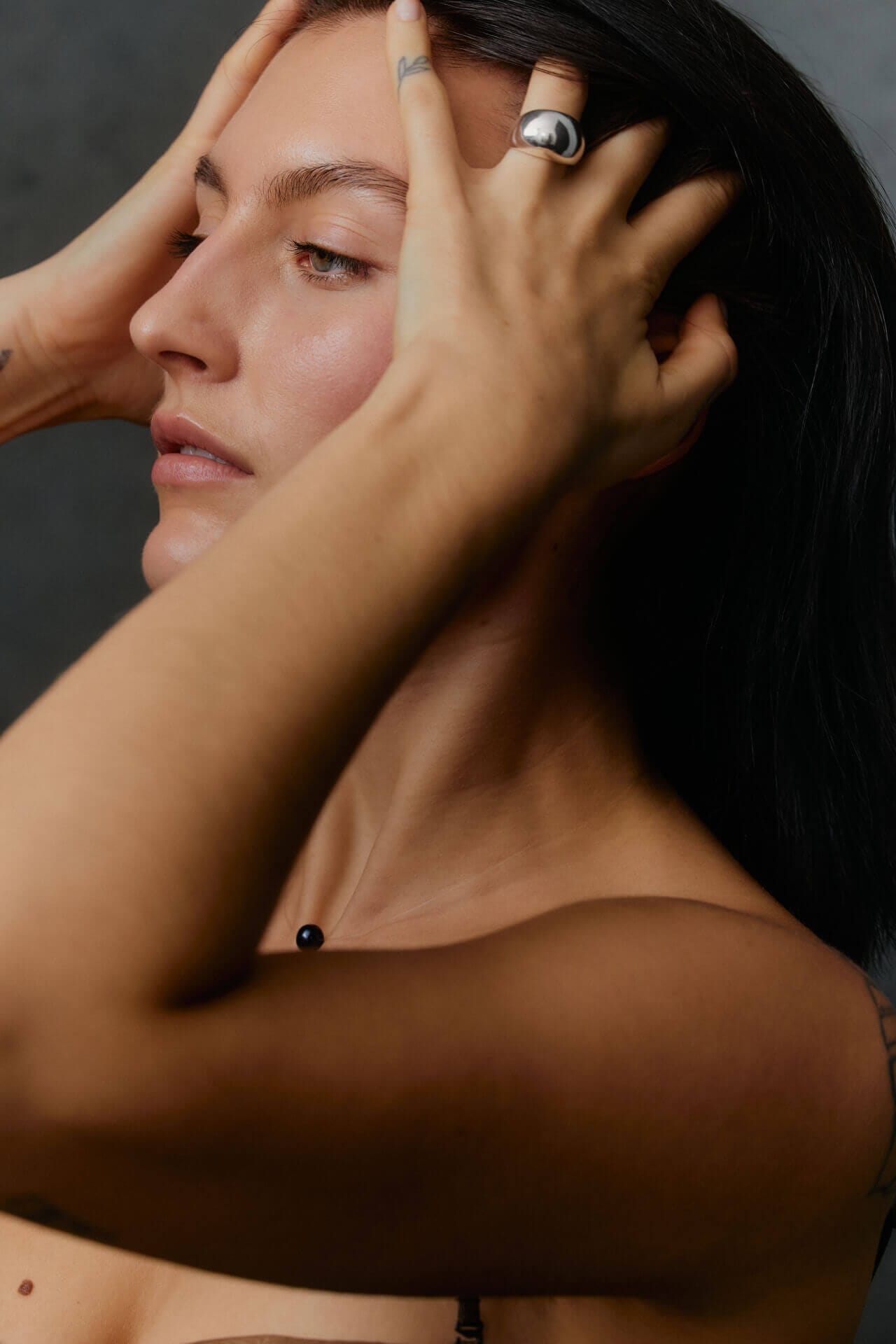 Person touching head with hands, side profile.