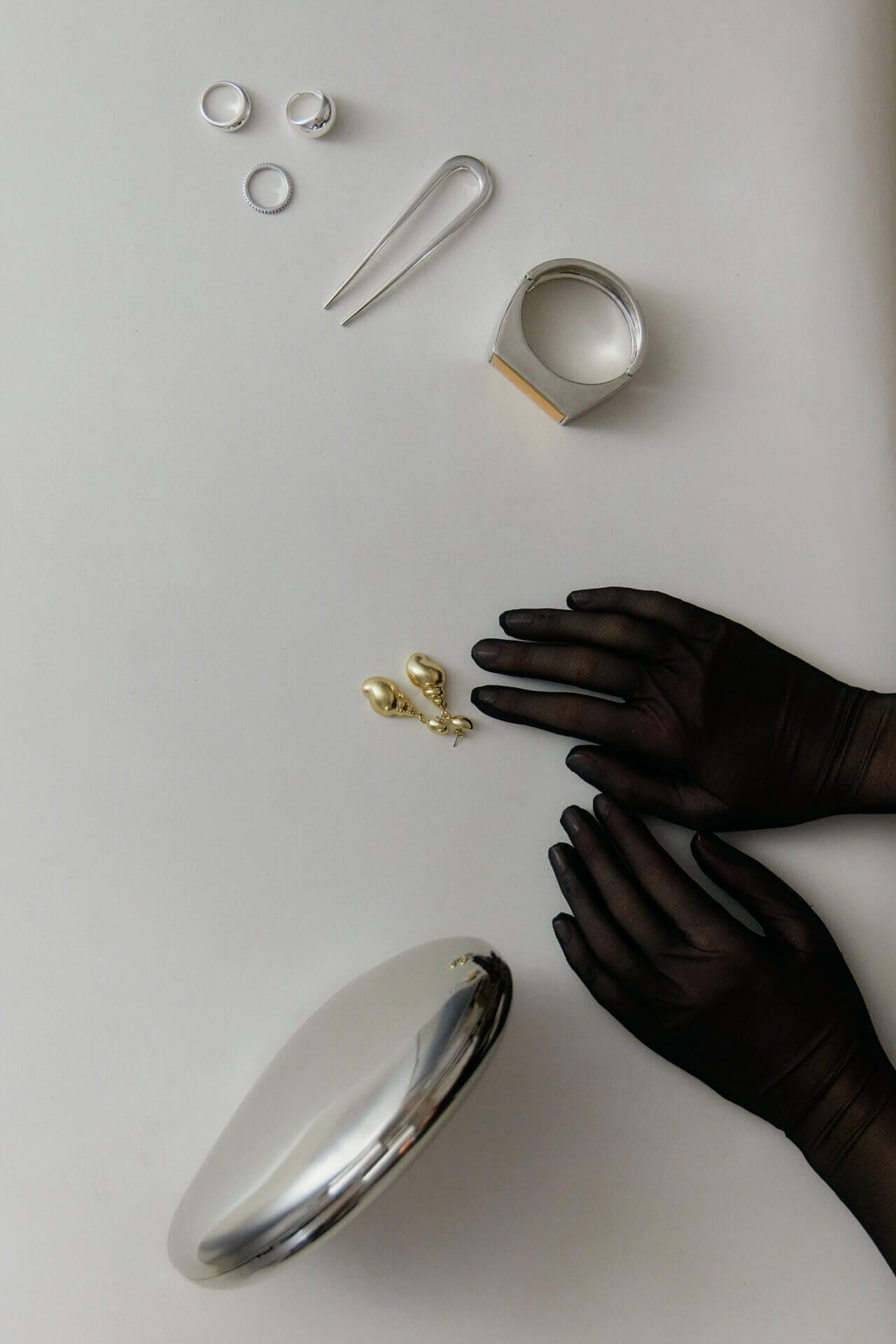 Gloved hands with jewelry and accessories displayed.