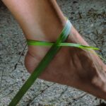 Bare foot with green grass ankle bracelet.