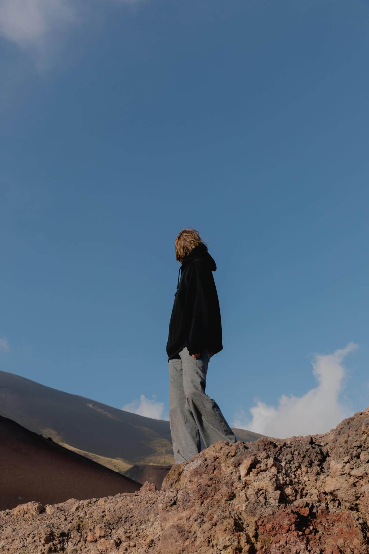Person standing on rocky terrain, blue sky.
