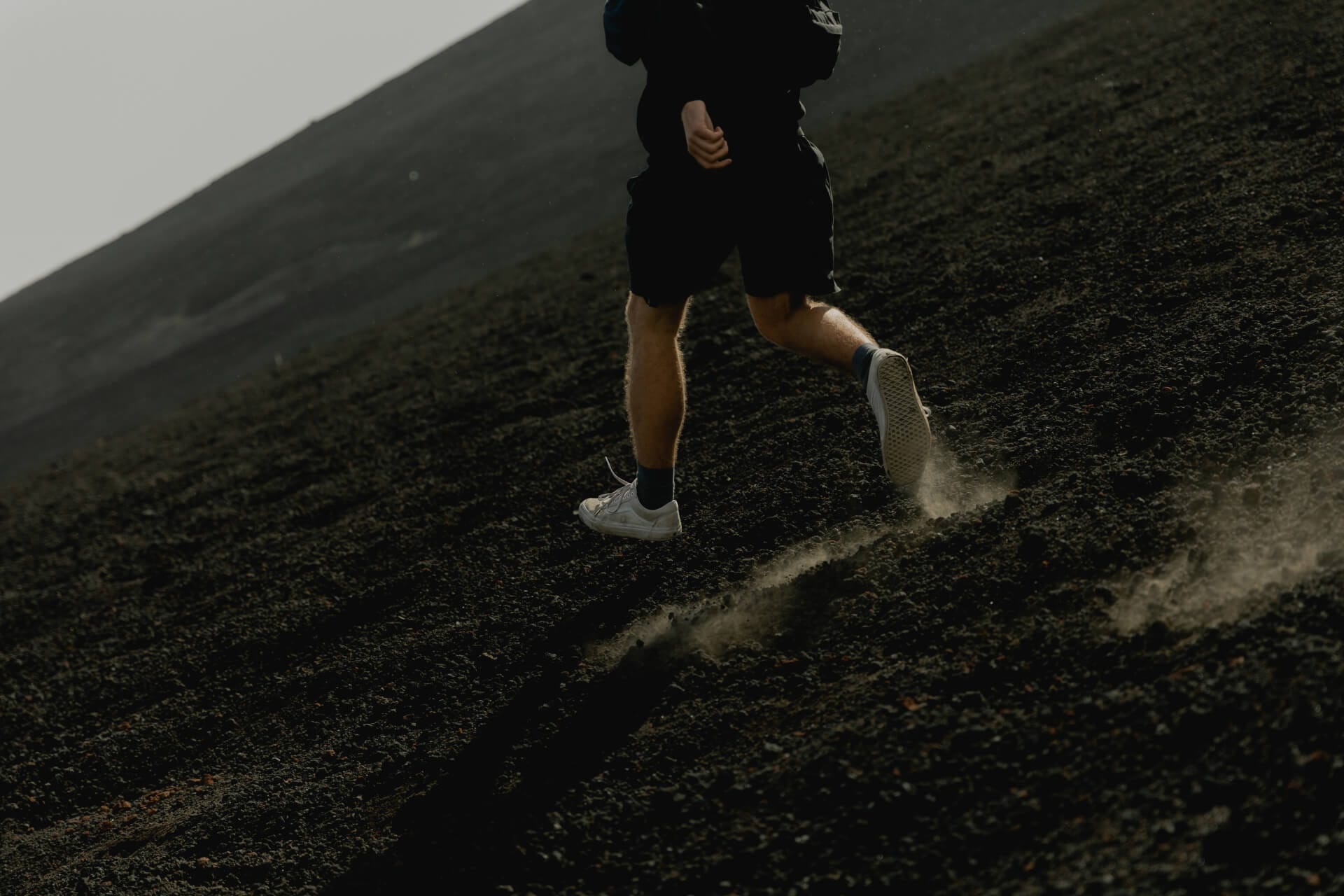 Person running on dark, dusty terrain.