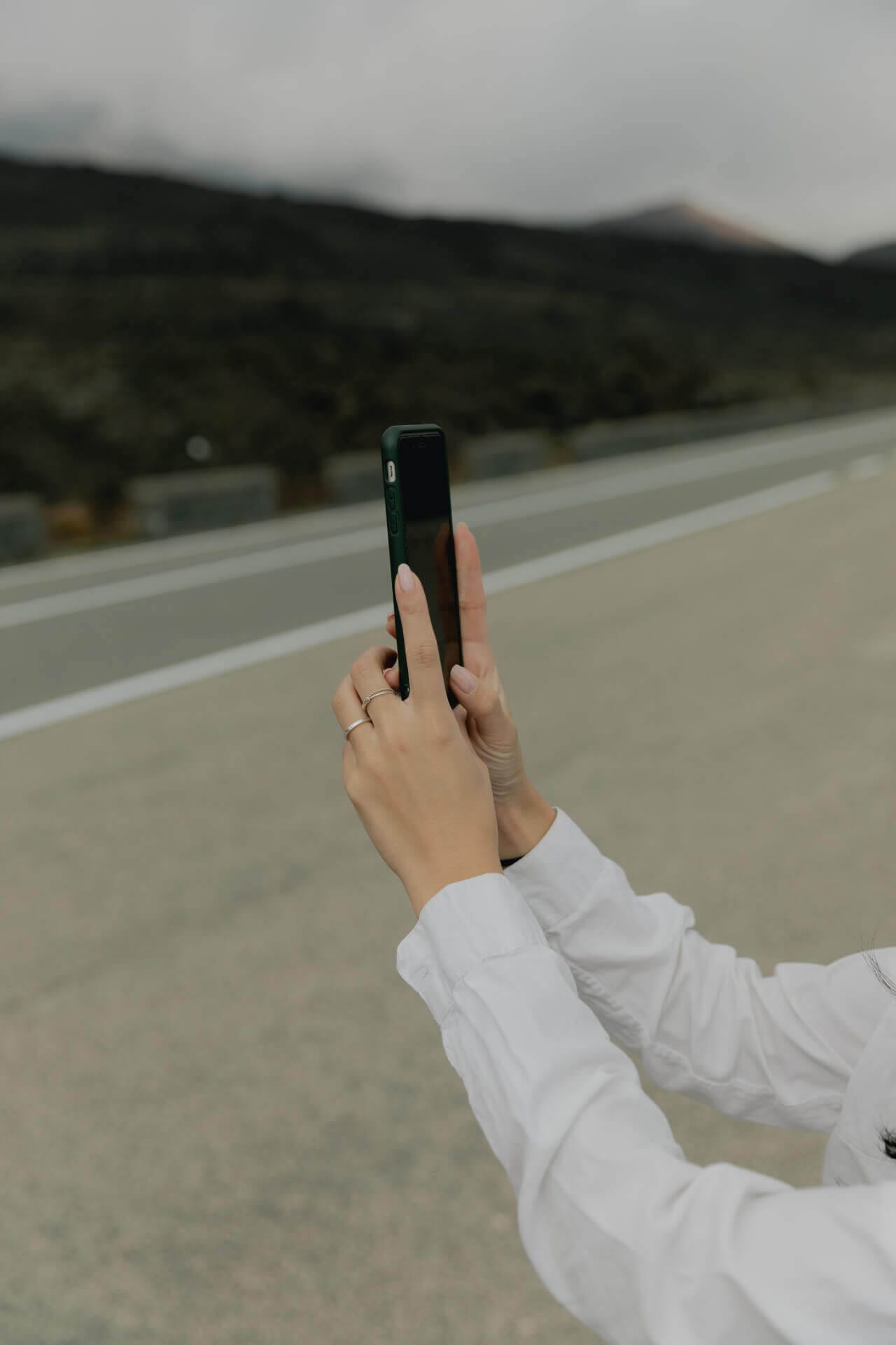 Person taking photo on empty road.
