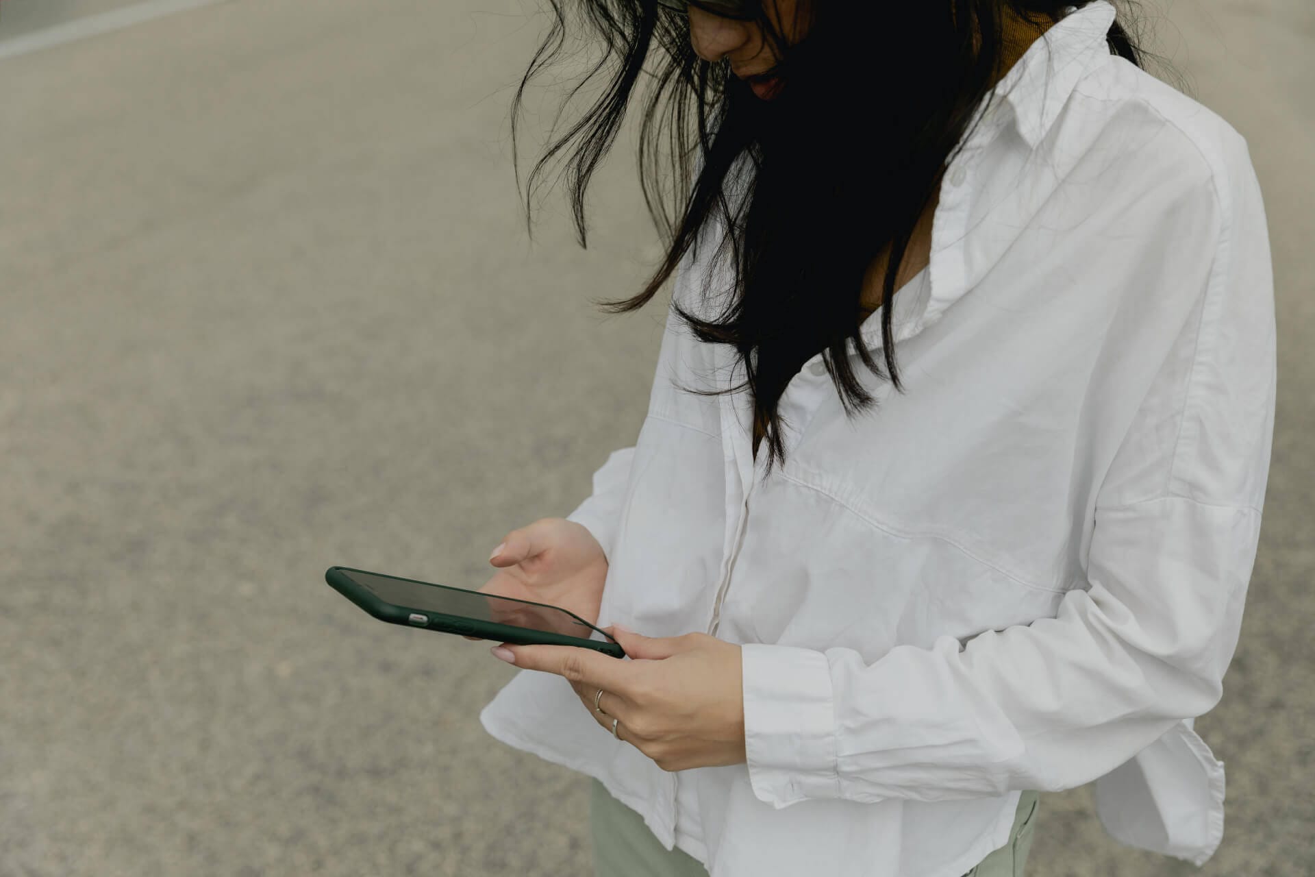 Woman looking at phone outdoors.