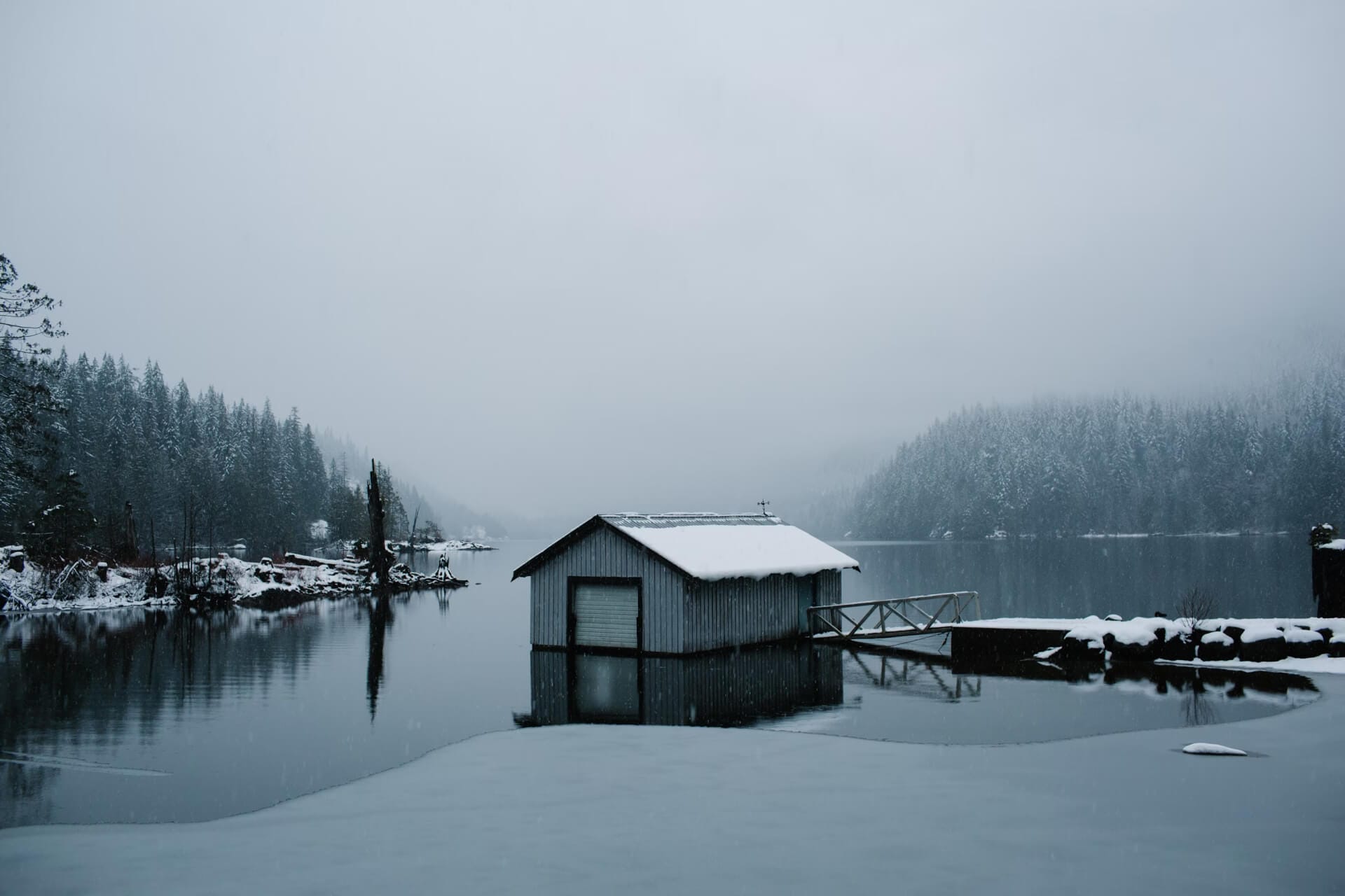 Snowy boathouse on a calm winter lake.