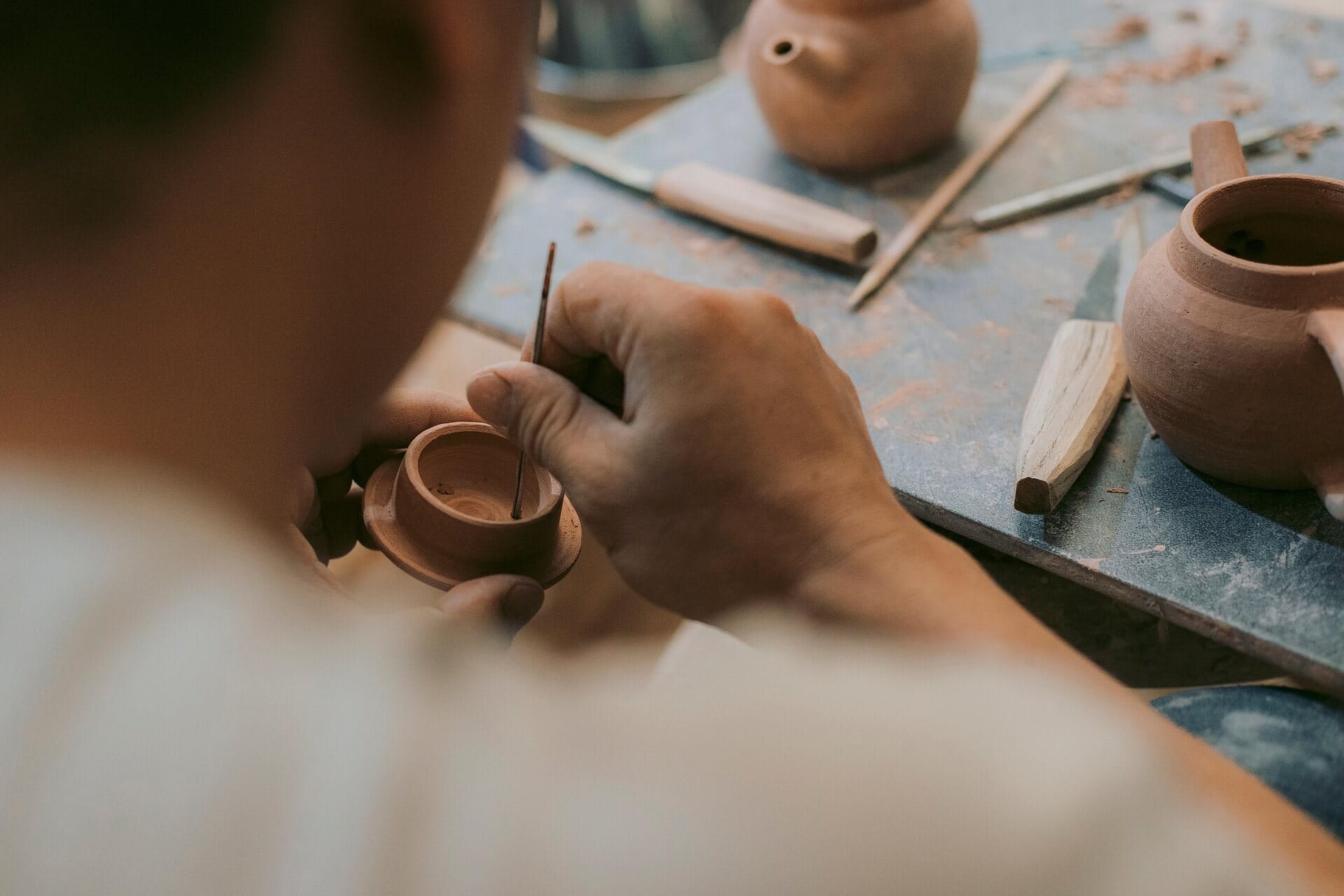 Person crafting pottery with carving tools.
