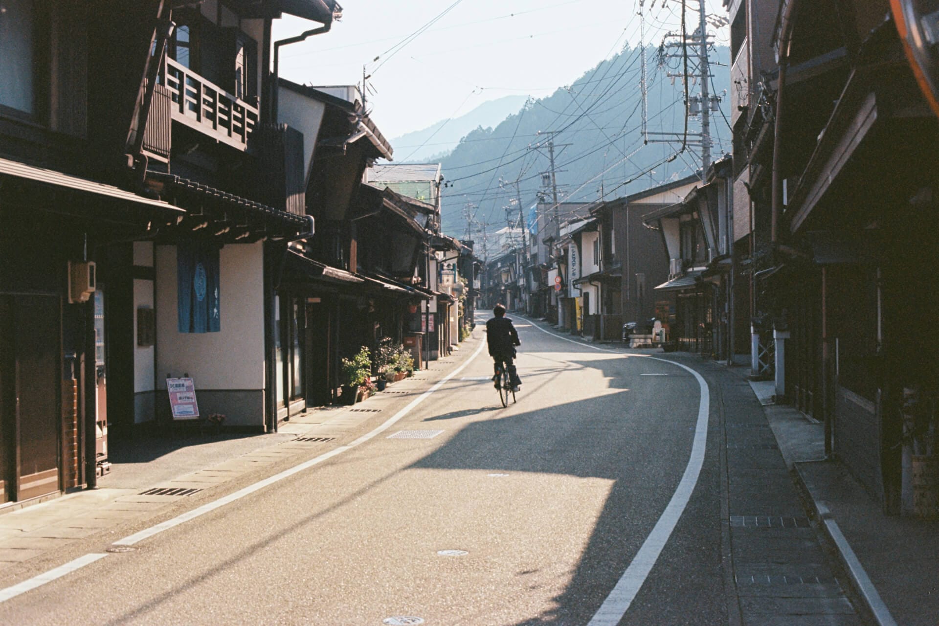 Cyclist on quiet street with traditional buildings.