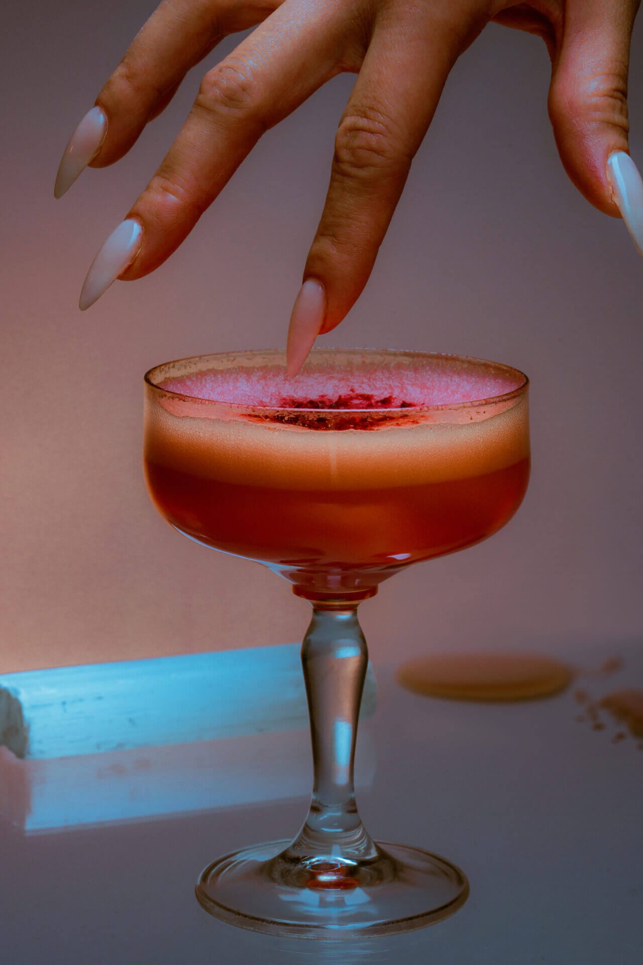 Hand reaching for a cocktail glass.