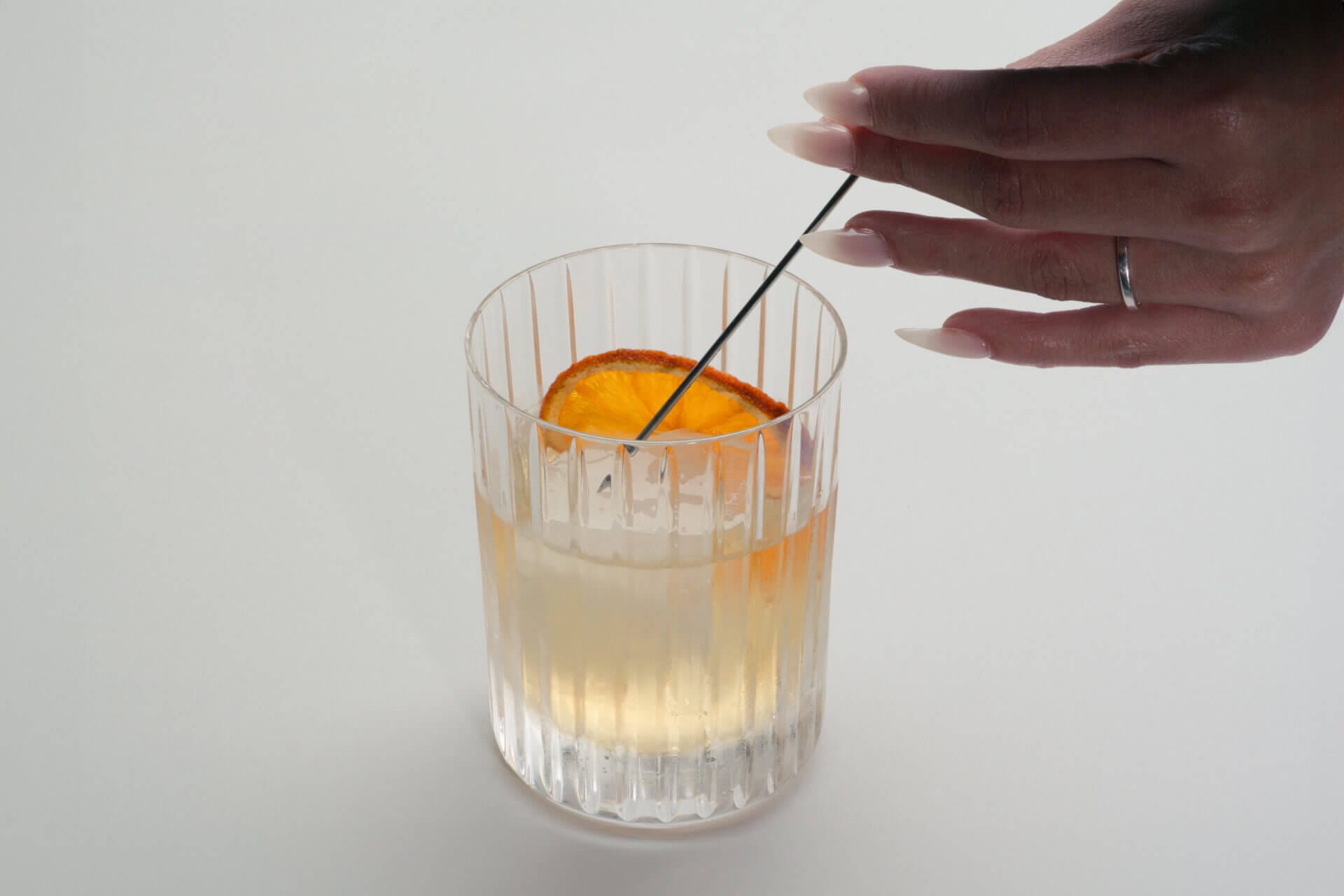 Hand garnishing cocktail with orange slice.