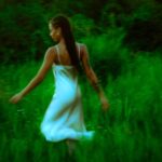 Woman in white dress walking through field.