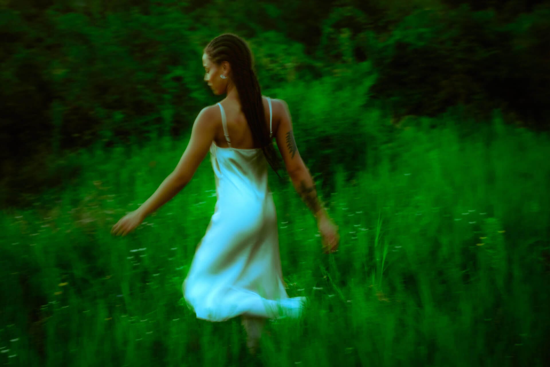 Woman in white dress walking through field.