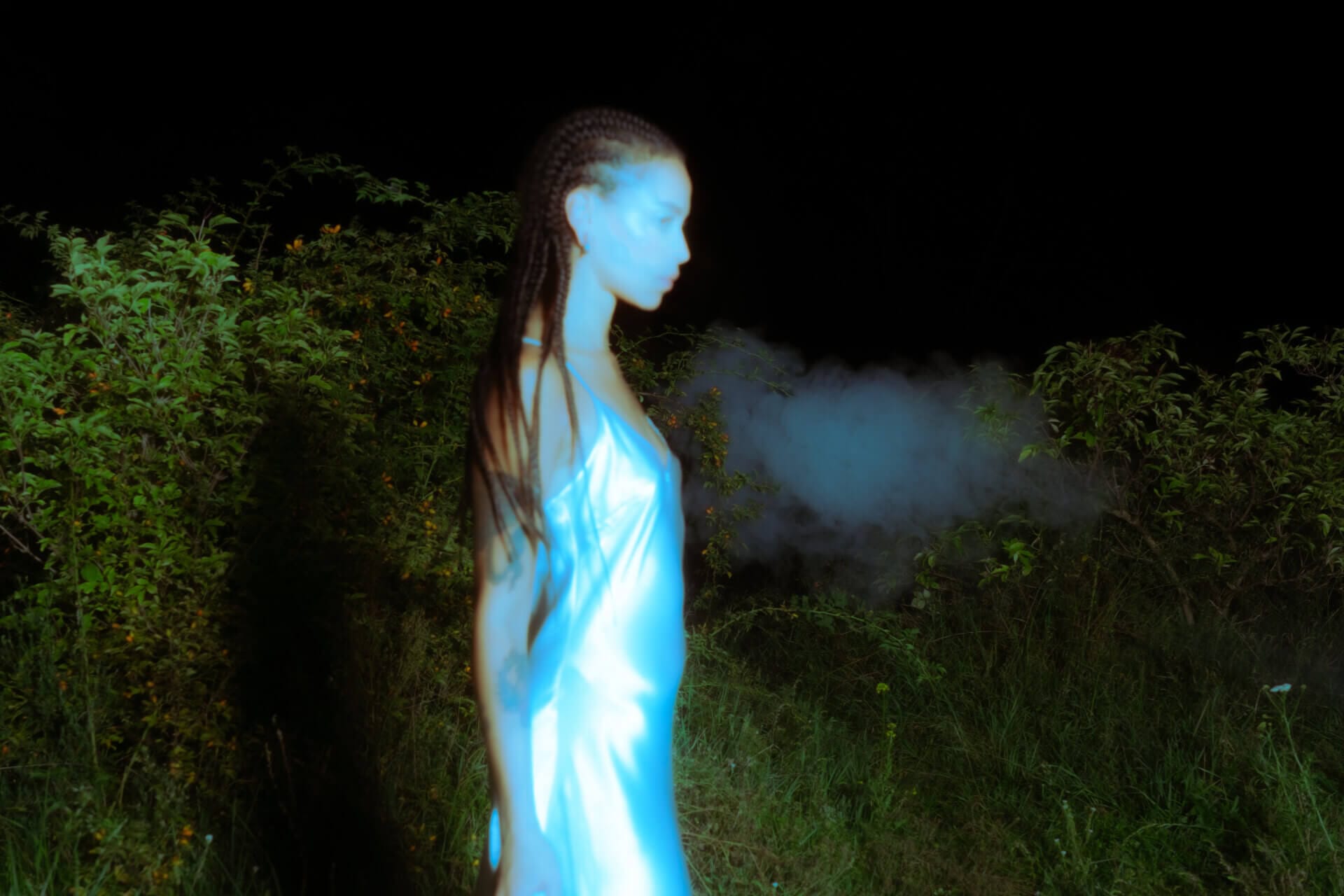 Person in blue light, exhaling mist outdoors.