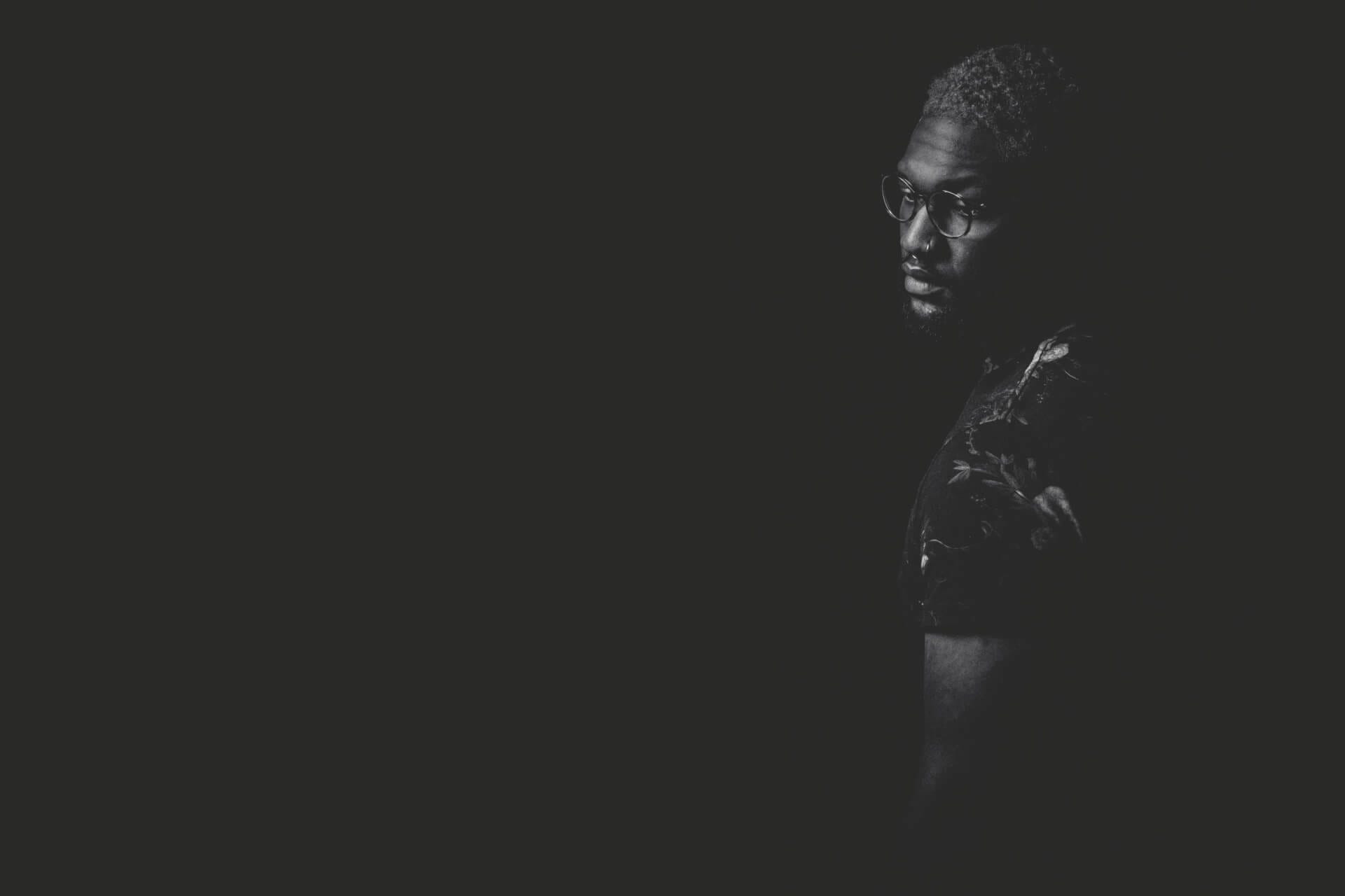 Man in dark, minimal lighting portrait.
